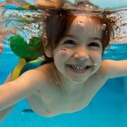 Kind im Schwimmbecken unter Wasser
